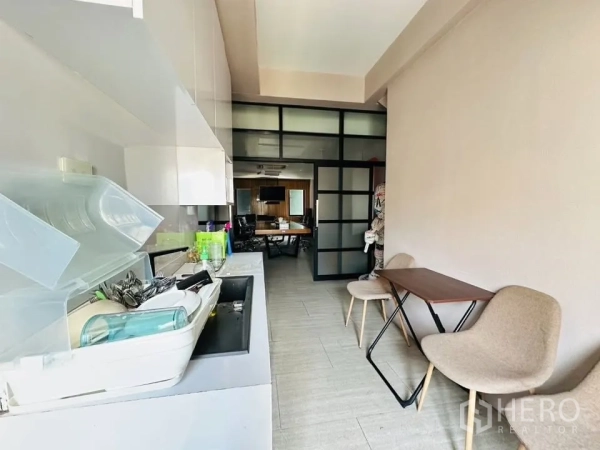 Shophouse for sale in Watthana, Bangkok - Compact pantry with countertop and sink leading to a glass-partitioned office or meeting room.