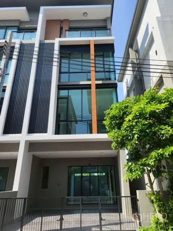 Home Office for rent in Bueng Kum, Bangkok - Modern multi-level home office exterior with large glass windows, vertical fins, and a gated covered carport in Bueng Kum.