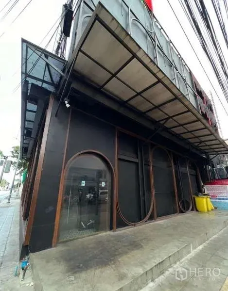 店屋 出租 - 转角店屋外立面，黑色外墙，拱形橱窗与人行道雨棚。