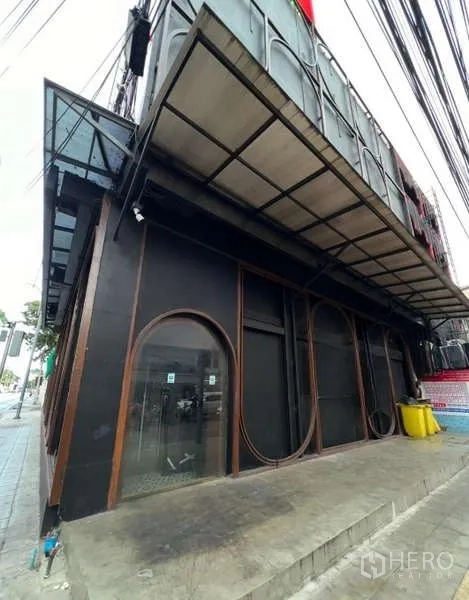 店屋 出租 - 转角店屋外立面，黑色外墙，拱形橱窗与人行道雨棚。