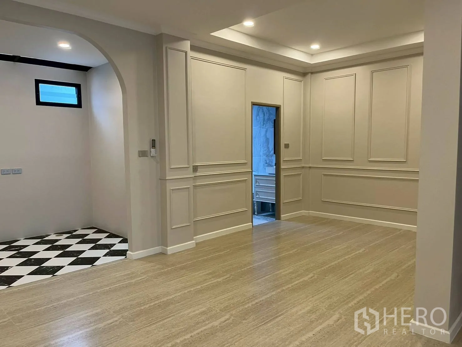 Townhouse for rent in Khlong Toei, Bangkok - Open-plan living space with arched entry to kitchen area and paneled walls.