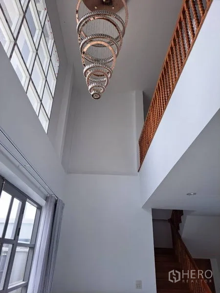 Detached House for rent in Prawet, Bangkok - Double-height foyer with statement chandelier and wooden staircase.
