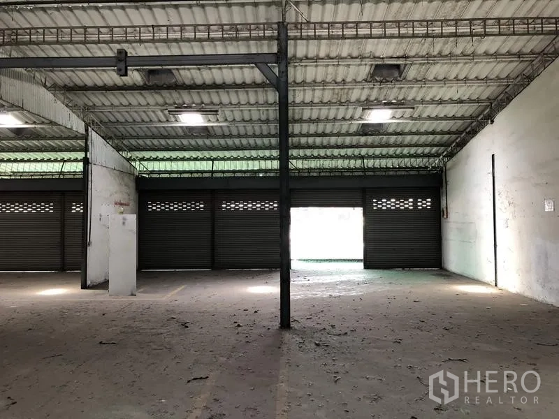 Warehouse for rent in Khlong Luang, Pathum Thani - Interior view toward multiple roller shutters providing loading access and airflow.