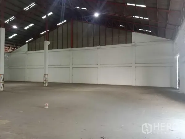 Factory for rent in Samut Prakan - Open factory floor with high roof, red steel trusses, and white walls.