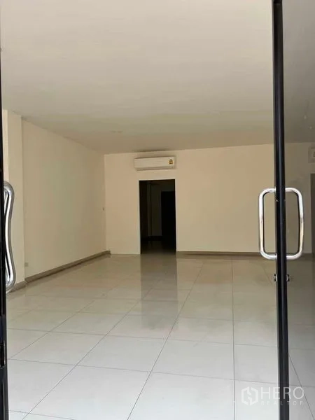 Home Office for rent in Bang Kapi, Bangkok - Bright open-plan ground floor with white tiled flooring, recessed lights and a wall-mounted air conditioner.