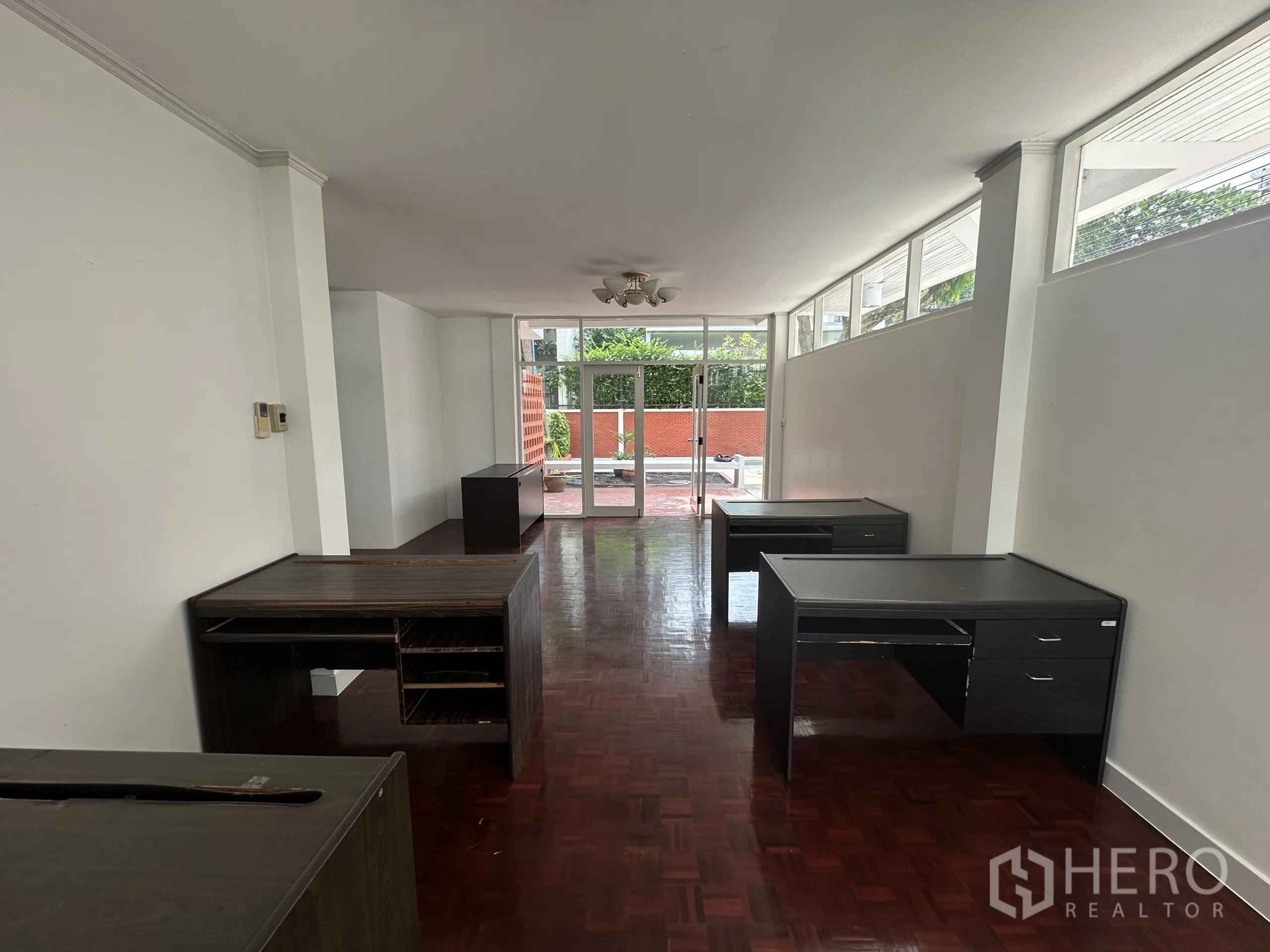带办公室的家 出租在Watthana, Bangkok - 细长工作区通向玻璃门外的前庭，沿墙摆放深色书桌。