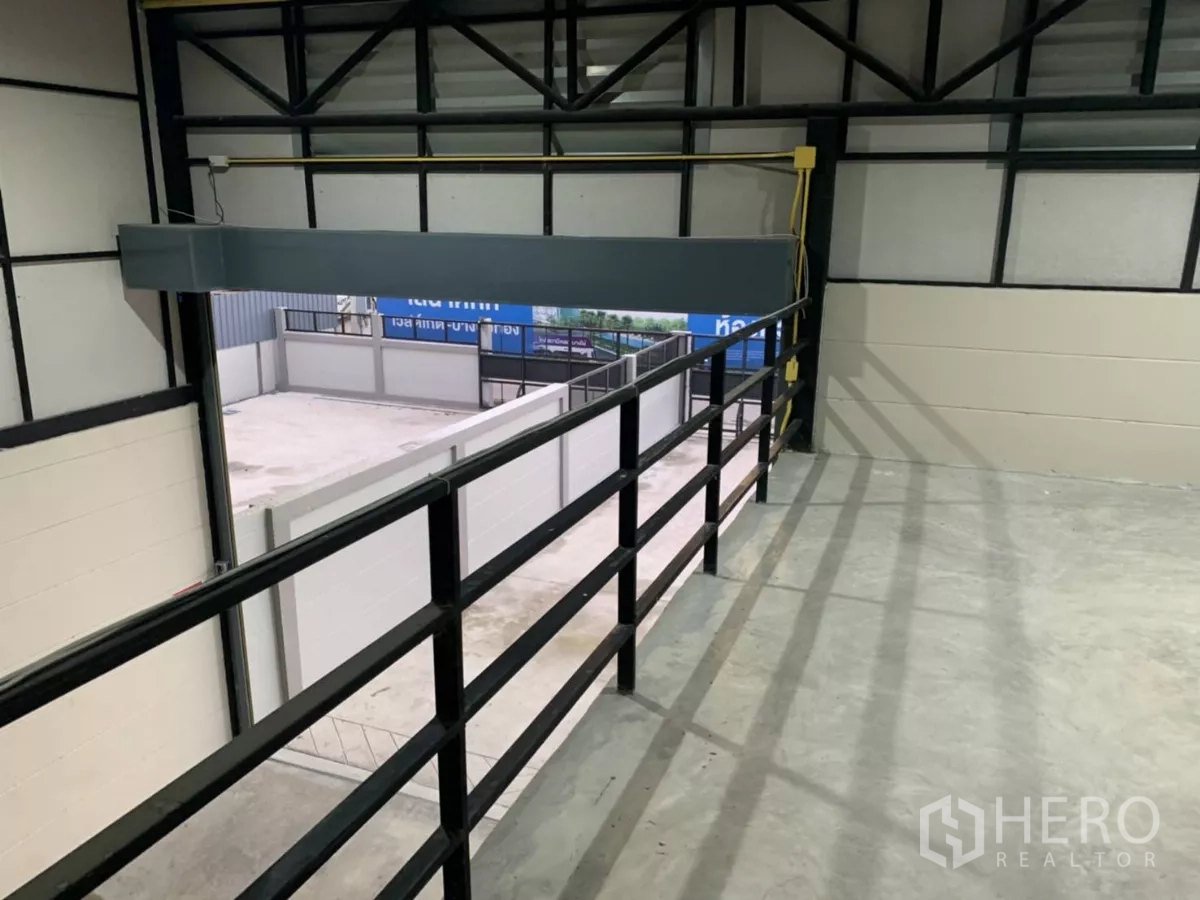 Warehouse for rent in Bang Bua Thong, Nonthaburi - View from the mezzanine level over the loading area with metal railing and high truss roof.