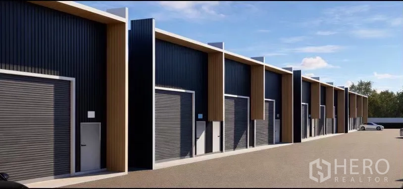 Warehouse for rent in Wang Thonglang, Bangkok - Close view of warehouse bays with roller shutter doors and side personnel doors along a paved lane.