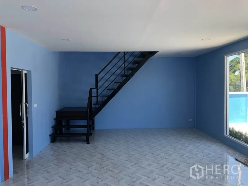 Warehouse for rent or sale in Sai Noi, Nonthaburi - Ground-floor office with blue walls, large window and black metal staircase to the second floor.