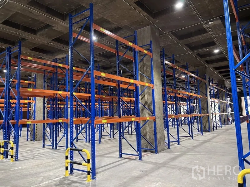 Warehouse for rent in Chatuchak, Bangkok - Detail of blue-framed pallet racks with yellow safety guards on a concrete warehouse floor in Chatuchak.