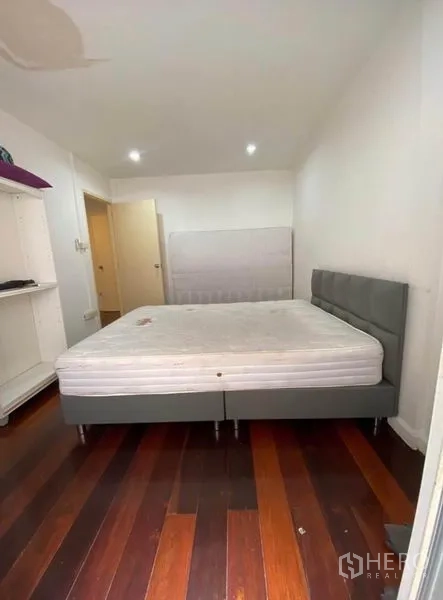 Townhouse for rent in Khlong Toei, Bangkok - Second bedroom with double bed, built-in shelving, and polished wood flooring.