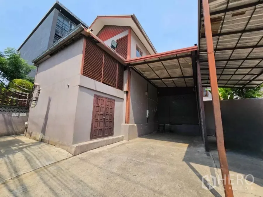 Warehouse for rent in Chatuchak, Bangkok - Driveway and front facade of the warehouse with canopy and roller shutter door.