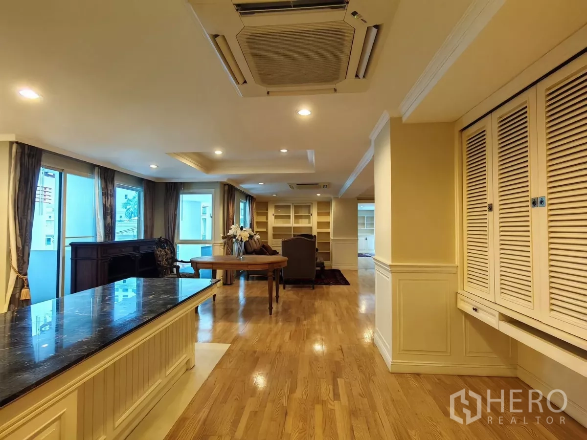 Condominium for rent in Pathum Wan, Bangkok - Open-plan living and kitchen with marble island, wood floors, built-in cabinetry and cassette AC in a Bangkok condo.