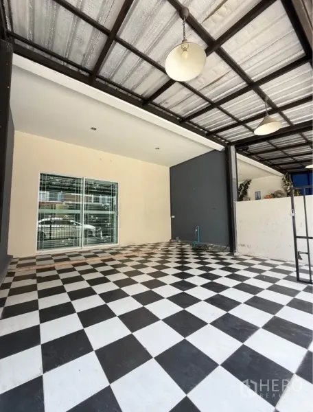Townhouse for rent in Suan Luang, Bangkok - Covered carport with black-and-white checker floor and pendant lights.