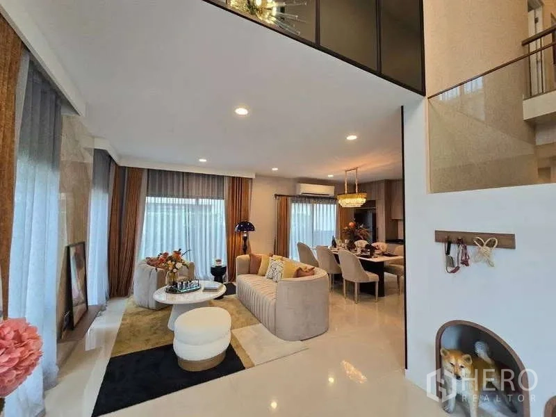 Detached House for rent in Bang Kapi, Bangkok - Open-plan living and dining area with sectional sofa and sheer curtains.
