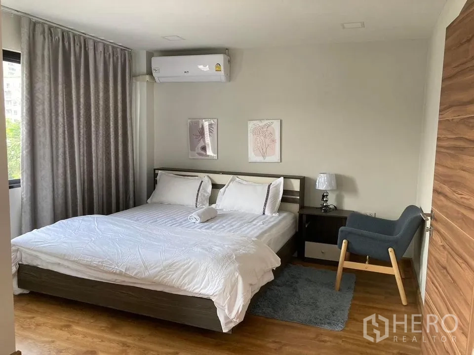 Detached House for rent in Khlong Toei, Bangkok - Bedroom with king bed, grey curtains, armchair and wood floors