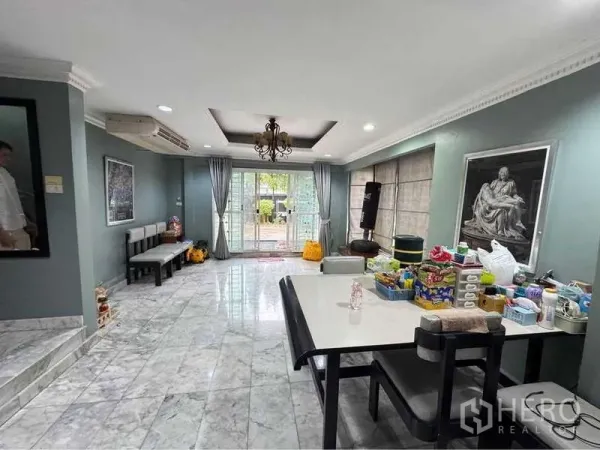 Detached House for rent in Suan Luang, Bangkok - Dining zone with marble floor opening to sliding glass doors to the patio, chandelier and grey curtains.