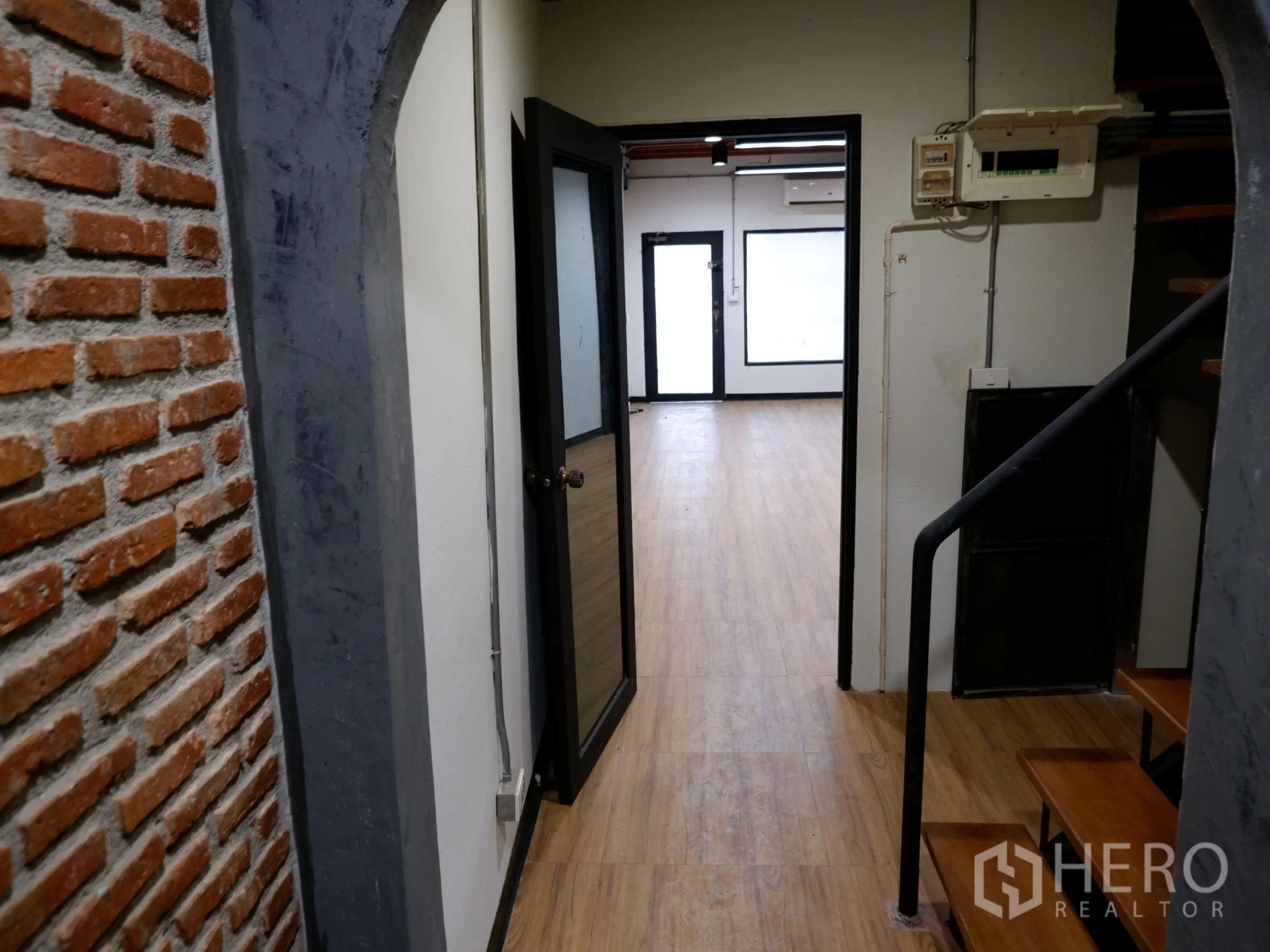 Home Office for sale in Bang Rak, Bangkok - Industrial-style corridor with exposed brick, black metal staircase and laminated wood floors.