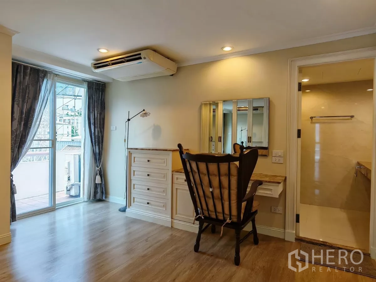 Condominium for rent in Pathum Wan, Bangkok - Room with balcony access, built-in vanity and wood floors.