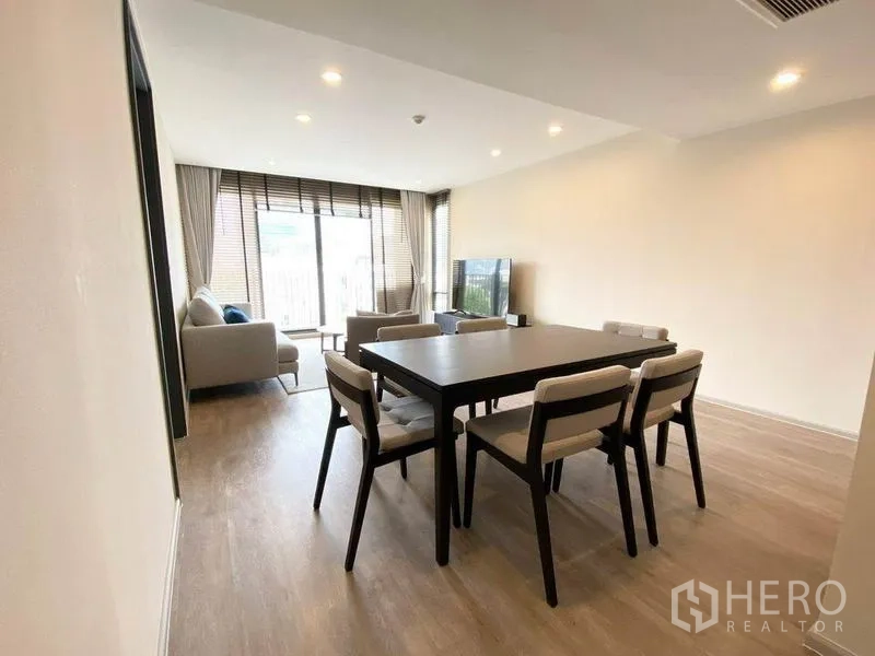 Condominium for rent in Pathum Wan, Bangkok - Open-plan dining and living area with six-seat table, sofa set and sliding glass doors to the balcony.
