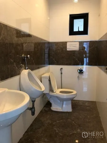 Factory for rent or sale in Samut Prakan - Clean restroom with toilet, urinals, sink and tiled walls and floor.