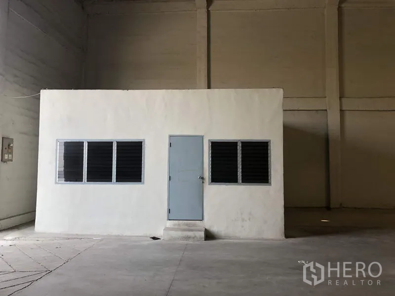Warehouse for rent in Khlong Luang, Pathum Thani - Internal office room inside the warehouse with windows and a single door.