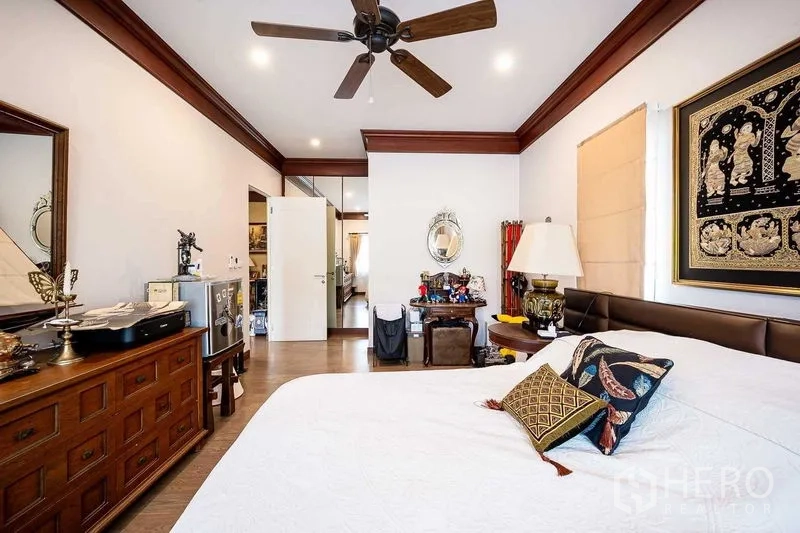 Detached House for sale in Prawet, Bangkok - Bedroom with ceiling fan, wooden furniture and framed artwork.