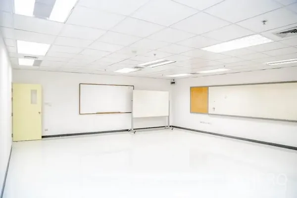 Office Space for rent in Bang Na, Bangkok - Empty office space with glossy floors, a mobile whiteboard, and wall boards along one side.
