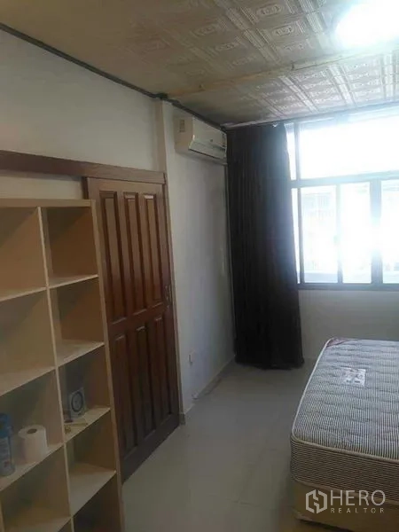Townhouse for rent - Bedroom with window, air conditioner, wooden door, and open shelving.