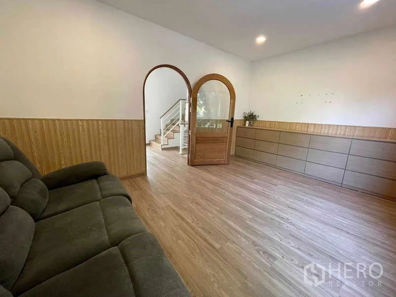 Townhouse for rent or sale in Bang Kapi, Bangkok - Cozy living room with sofa, arched doors, wood flooring and recessed lighting.