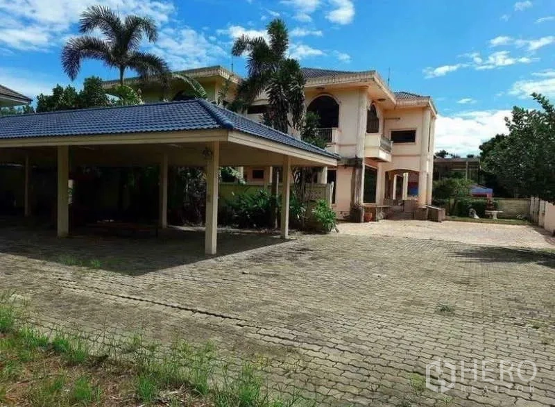 Detached House for sale in Prawet, Bangkok - Covered carport beside the two-storey home and a paved yard.