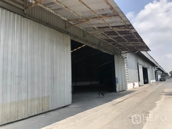 Warehouse for rent in Pathum Thani - Row of warehouse units with sliding metal doors and deep covered loading canopies.