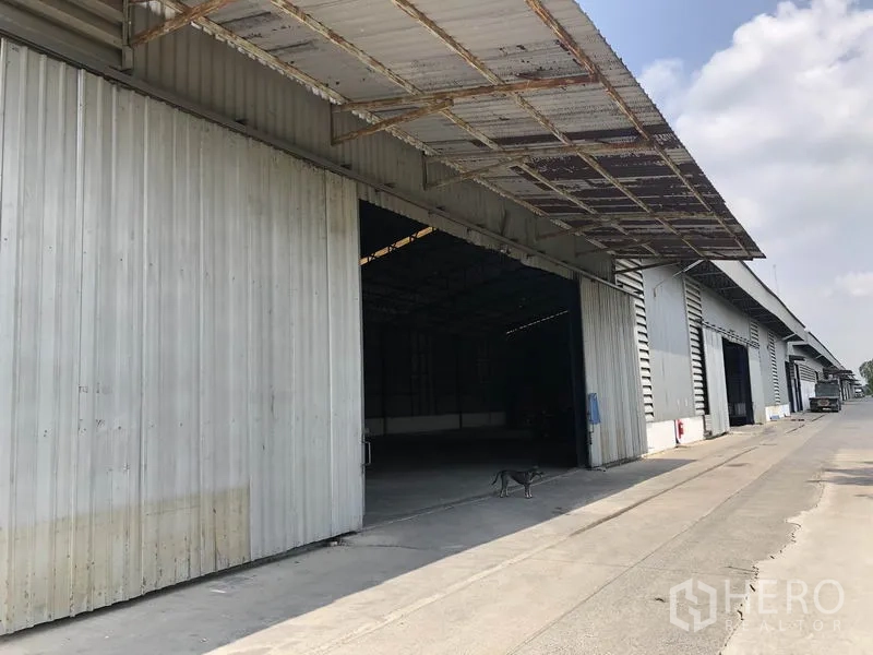Warehouse for rent in Pathum Thani - Row of warehouse units with sliding metal doors and deep covered loading canopies.