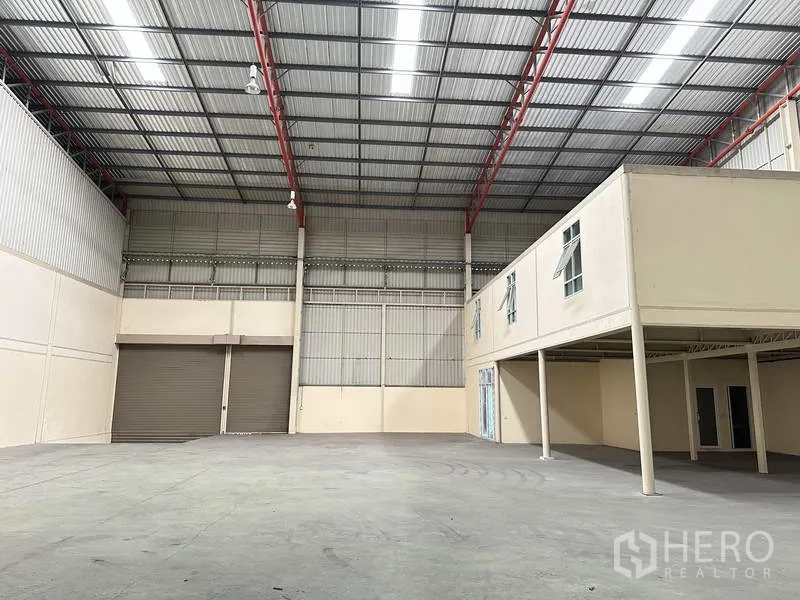 Factory for rent in Bang Phli, Samut Prakan - Open warehouse space with large roller door and mezzanine structure suited for office or storage.