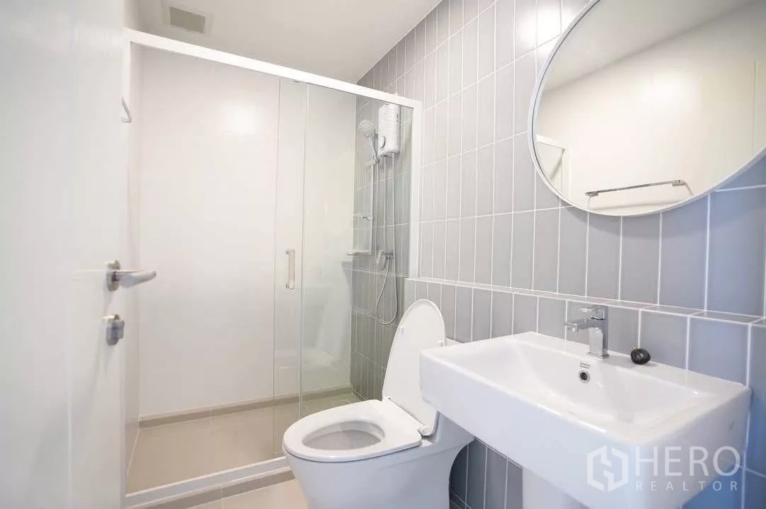Townhouse for rent in Bang Phli, Samut Prakan - Modern bathroom with gray tiled wall, glass shower and round mirror