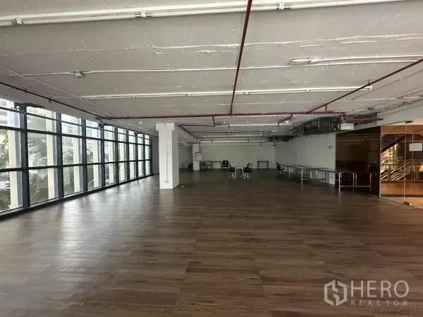 零售空间 出租 - 明亮零售大厅，整排窗墙、木纹地面与结构柱。