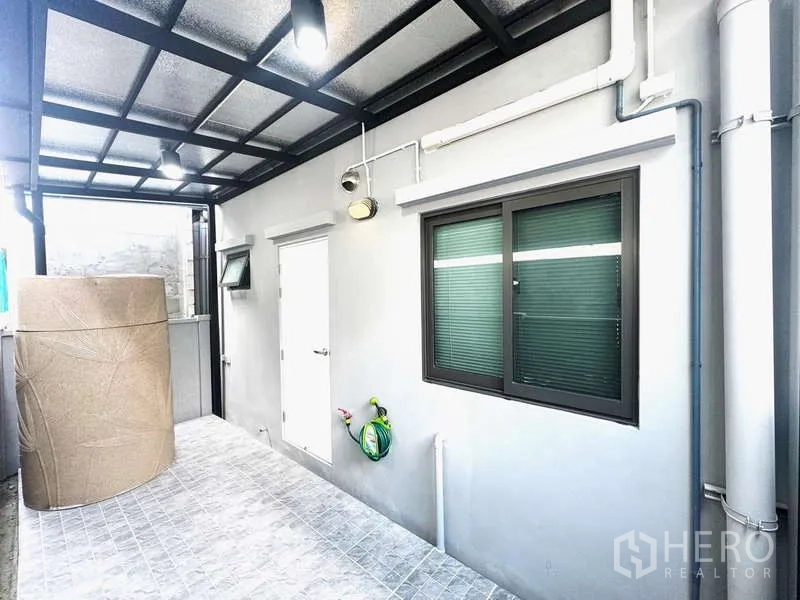 Townhouse for rent in Bang Phli, Samut Prakan - Rear service area with roof cover, window, doors and garden hose.