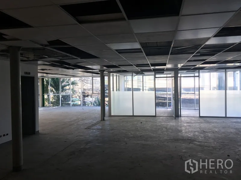 Warehouse for rent in Suan Luang, Bangkok - Large office area with frosted glass meeting rooms and grid ceiling overlooking the exterior.