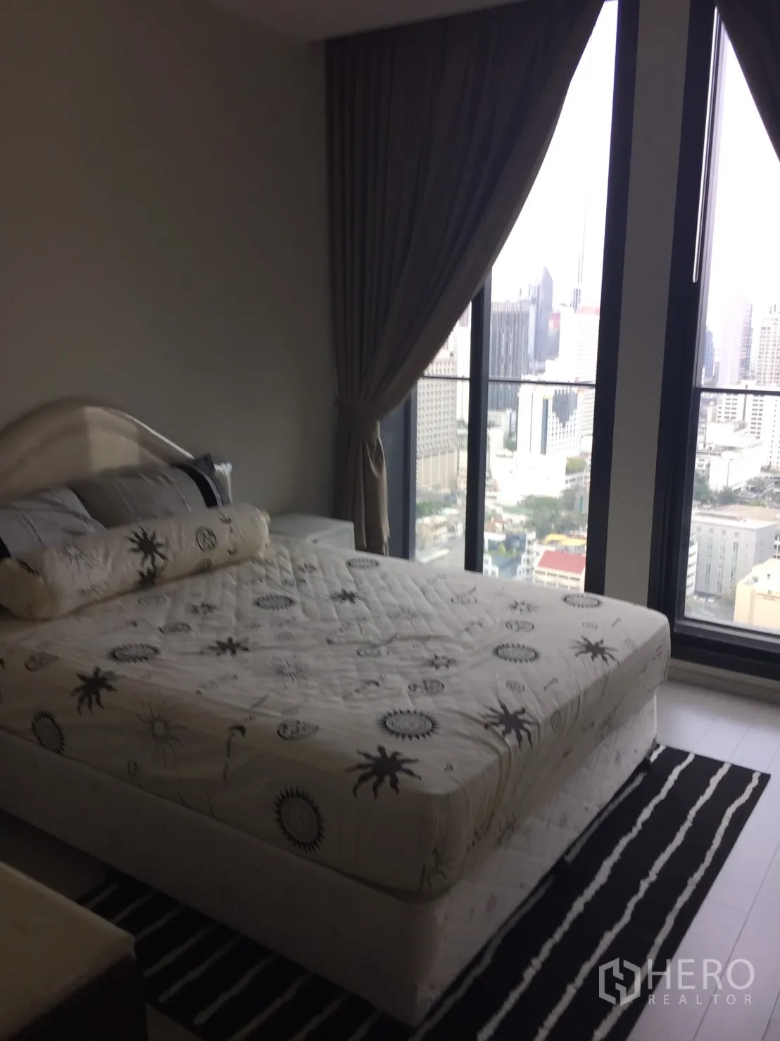 Condominium for rent in Pathum Wan, Bangkok - Bedroom with large bed, floor-to-ceiling windows, city view, and blackout curtains.