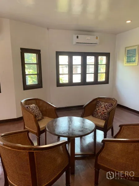 Townhouse for rent or sale in Phra Khanong, Bangkok - Corner sitting area with four rattan chairs around a round wooden table by windows.
