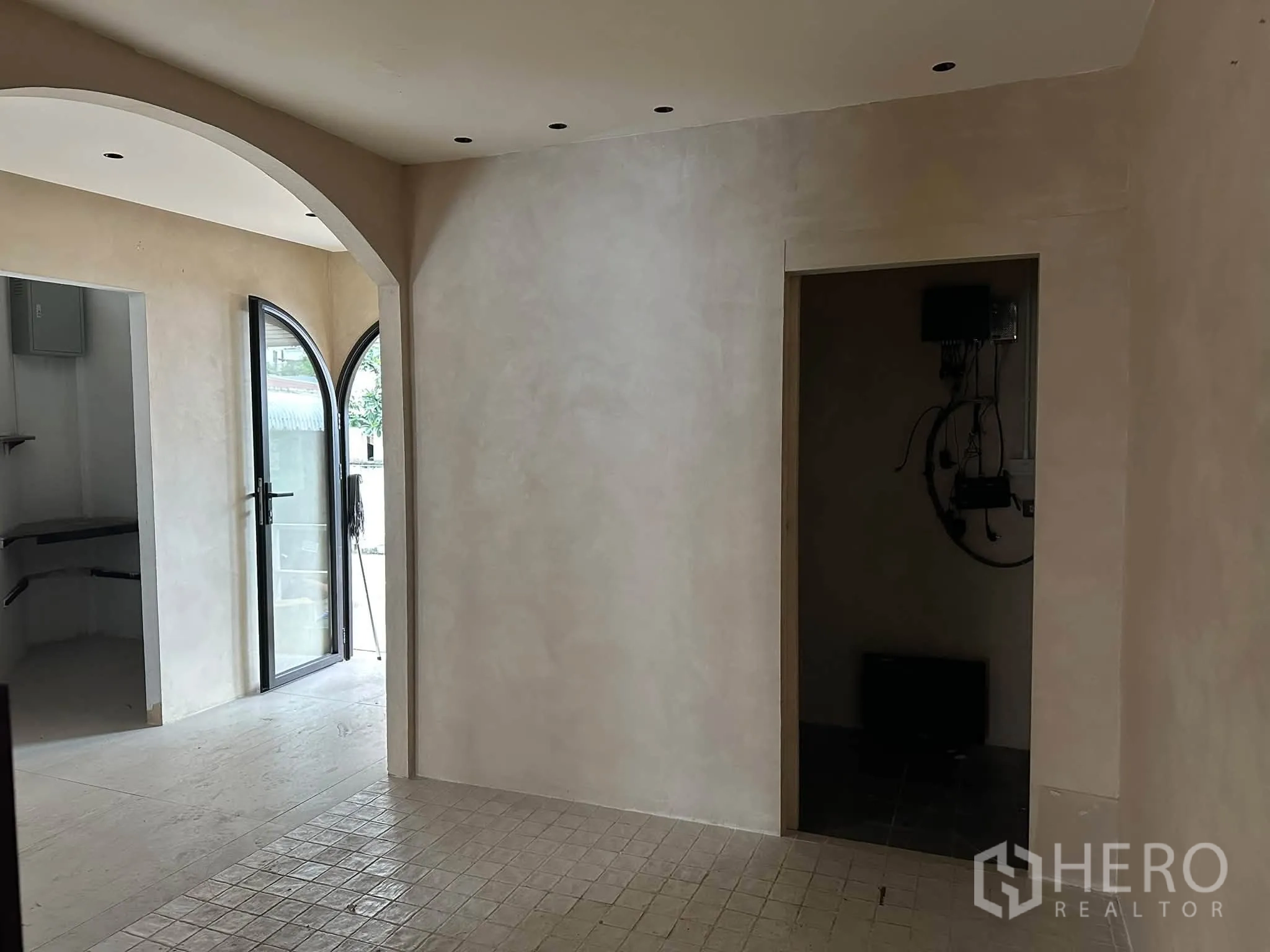 Retail Space for rent in Khlong Toei, Bangkok - Hallway with arched doorway and light-toned walls leading to small rooms and an exterior door.