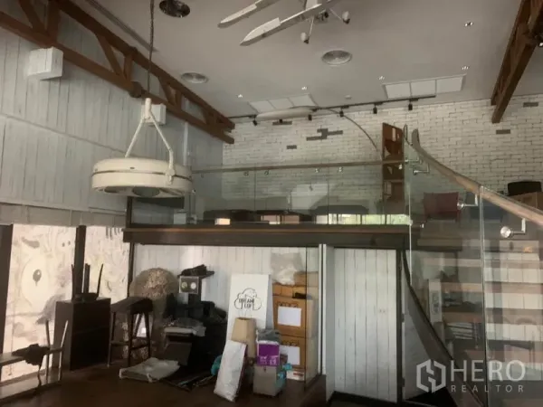 Retail Space for rent in Watthana, Bangkok - Double-height retail space with exposed beams, white brick walls, a glass mezzanine and pendant lighting.