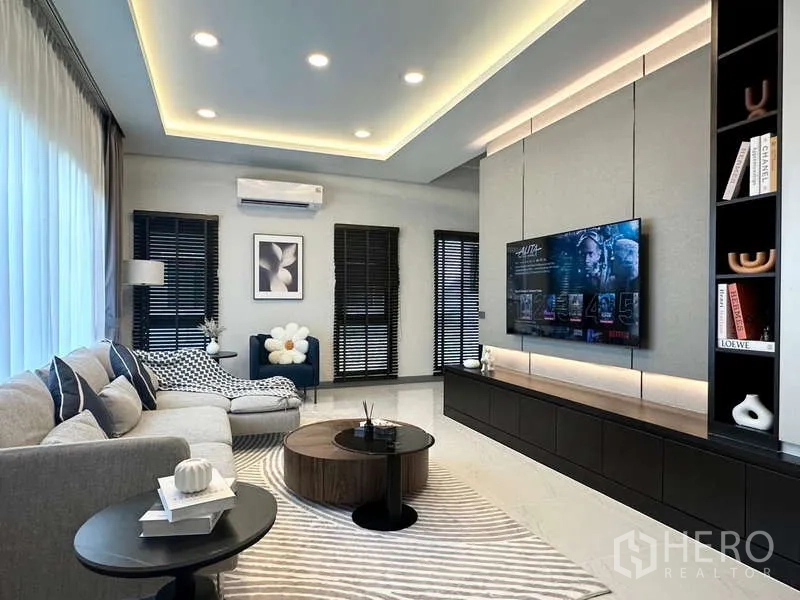 Detached House for rent in Bang Phli, Samut Prakan - Main living room with feature TV wall, recessed lighting and L-shaped sofa.