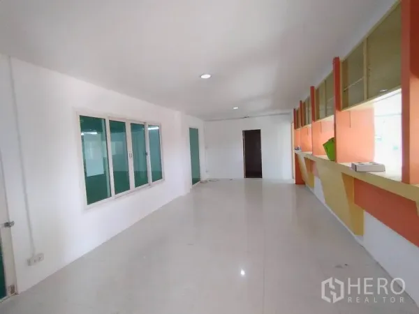 Factory for rent in Lam Luk Ka, Pathum Thani - Bright open-plan office with large windows, built-in shelving and glossy tile flooring.
