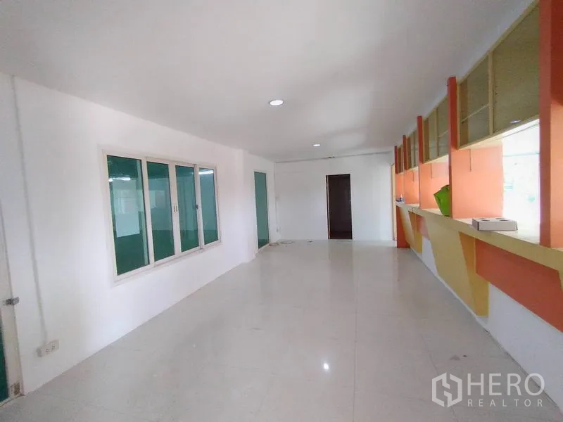 Factory for rent in Lam Luk Ka, Pathum Thani - Bright open-plan office with large windows, built-in shelving and glossy tile flooring.