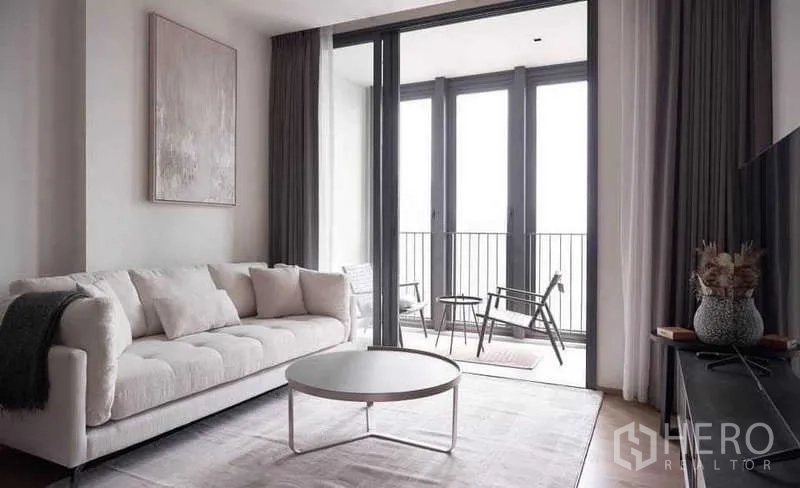 Condominium for rent or sale in Khlong Toei, Bangkok - Bright lounge with white sofa, TV unit, and large sliding glass doors to the balcony.