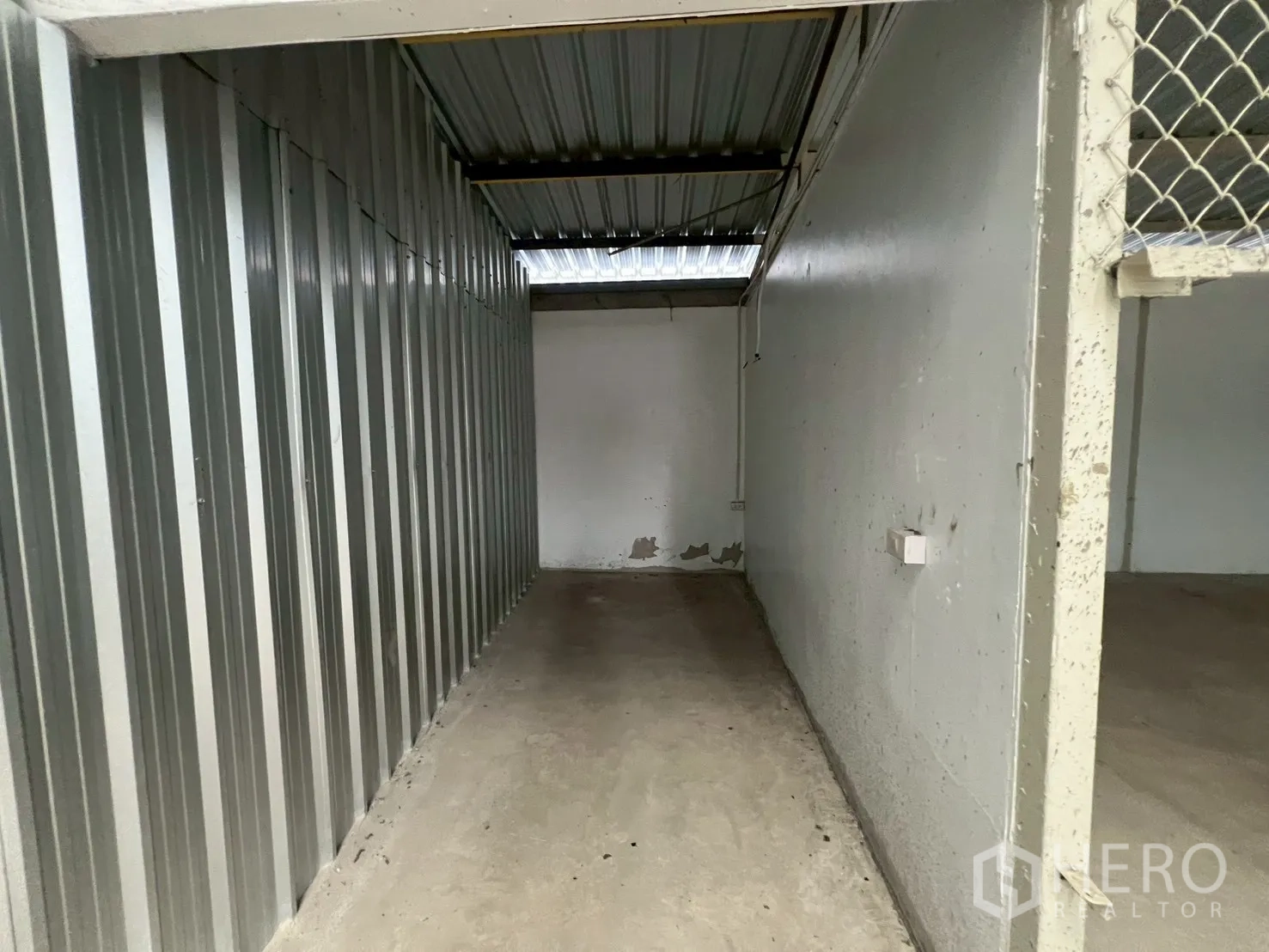 Warehouse for rent in Min Buri, Bangkok - Narrow side storage corridor with corrugated metal cladding and concrete floor.