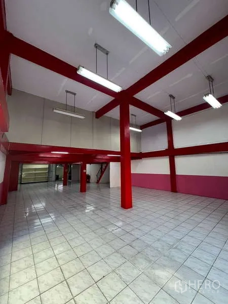 Shophouse for rent in Suan Luang, Bangkok - Alternate angle of tall retail hall with mezzanine potential and red beams.
