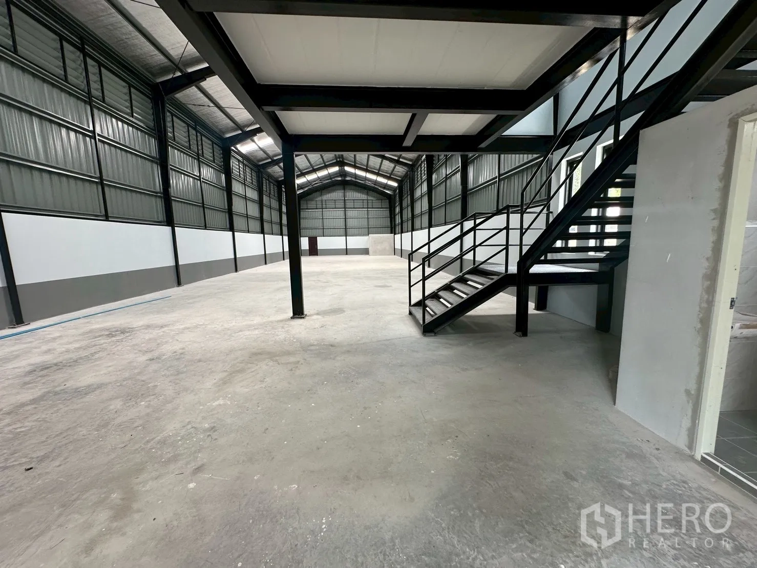 Warehouse for rent in Suan Luang, Bangkok - View of steel staircase and open workspace beneath the mezzanine in the warehouse.