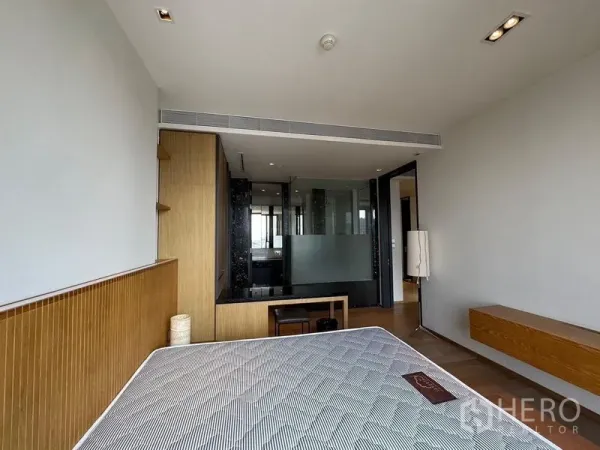 Condominium for rent - Bright bedroom with bed, built-in desk and a glass partition leading to the bathroom.